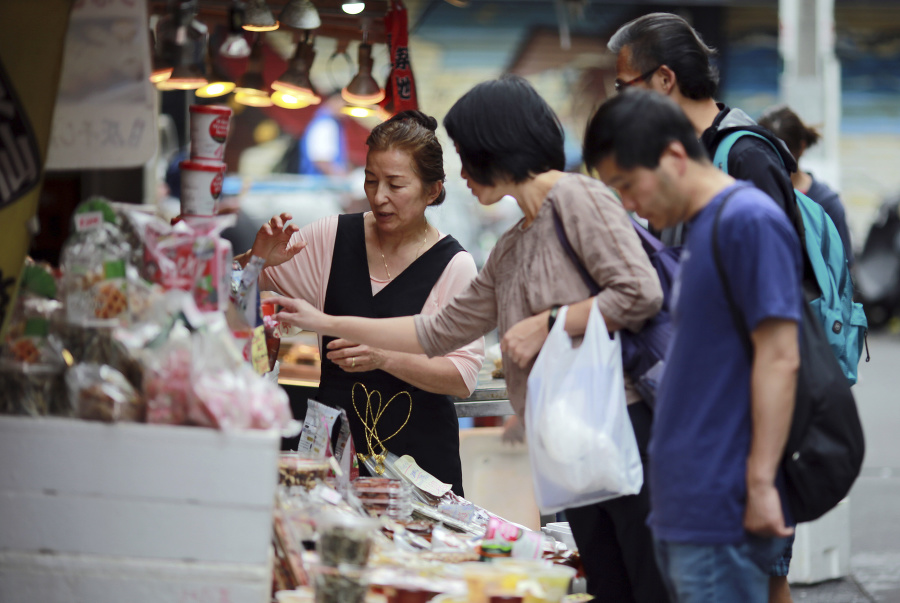 Predavačka sa rozpráva so zákazníčkou neďaleko jedného z najväčších trhov s rybami Cikiji šijó v Tokiu.