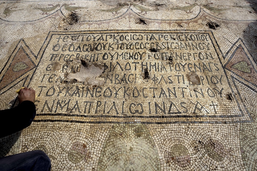 Šmulik Freireich z Izraelského úradu pre pamiatky (IAA) čistí nápis na mozaike.