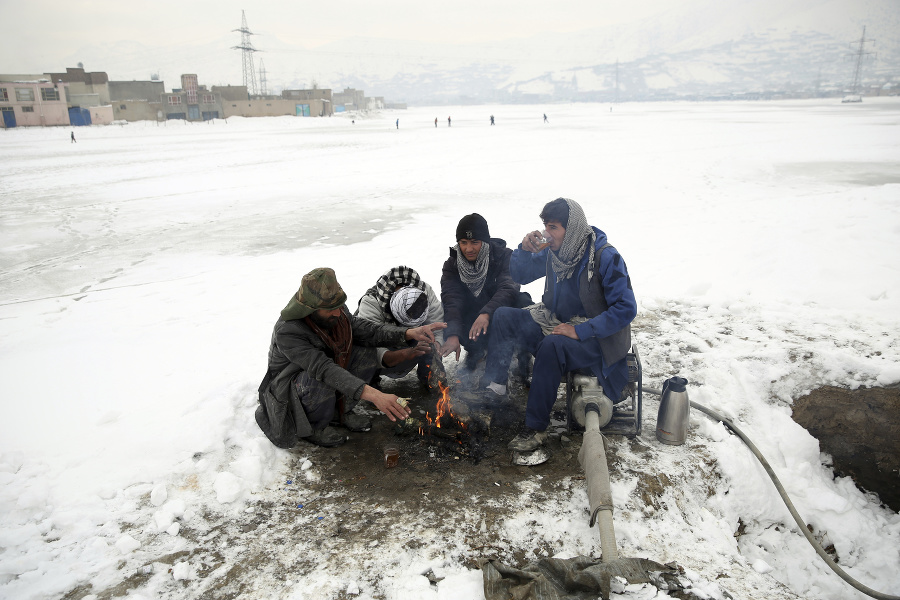 Ľudia sa zohrievajú pri ohni po hustom snežení v Kábule.