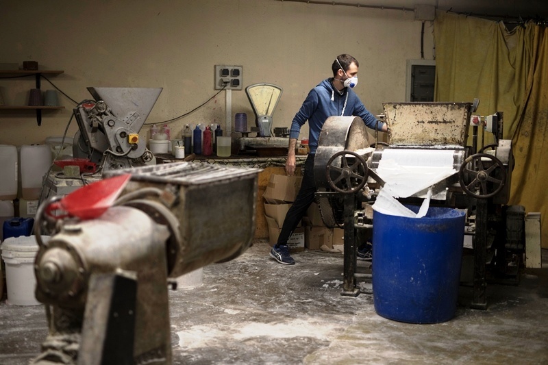 Zamestnanec s ochranným rúškom pracuje v rodinnej výrobni mydla.