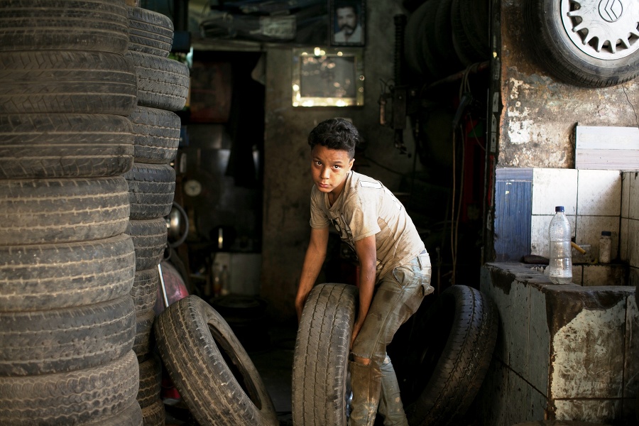 Chlapec nesie pneumatiku v opravovni v Káhire.