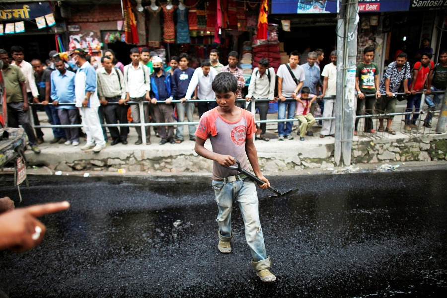 Supervízor dáva inštrukcie 13-ročnému chlapcovi počas opravy cesty v Káthmandu.