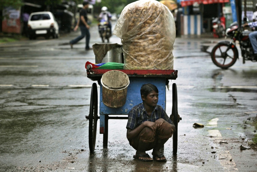 Chlapec predáva zemiaky na ulici počas dažďa v meste Bhúbanešvar.