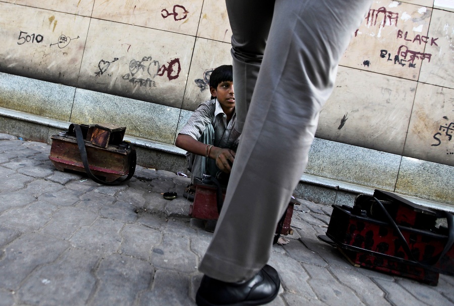 Chlapec čistí na ulici topánky v indickom meste Naí Dillí.