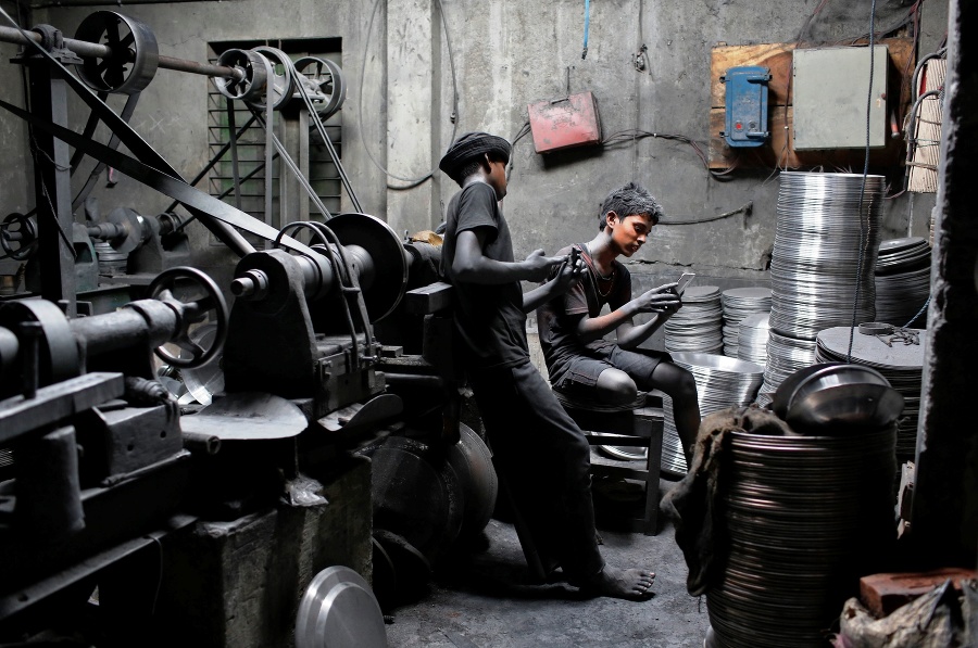11-roční chlapci Imran a Nizam pozerajú do mobilov počas pracovnej prestávky v továrni na kovové súčiastky.