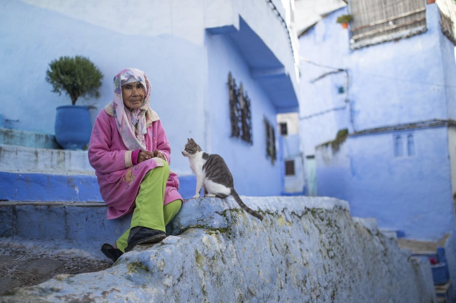 Staršia pani sedí vedľa svojej mačky pred domom v meste Šafšawán.