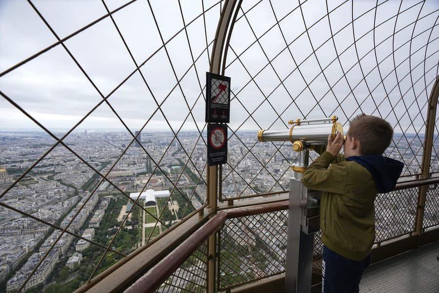 Návštevník sa pozerá cez ďalekohľad z Eiffelovej veže v Paríži.