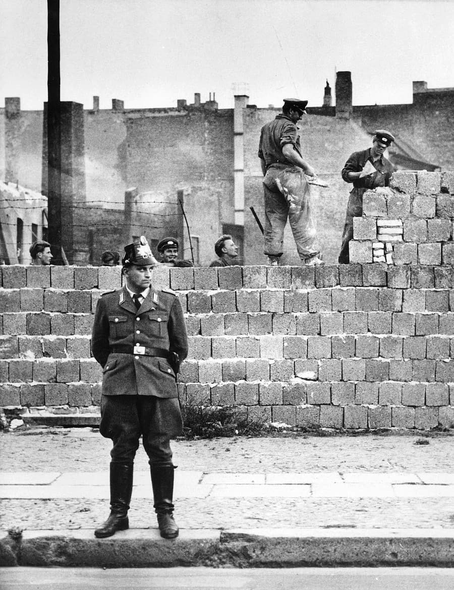 Na snímke zo 7. októbra 1961 berlínsky policajt stráži robotníkov pri stavbe múru.