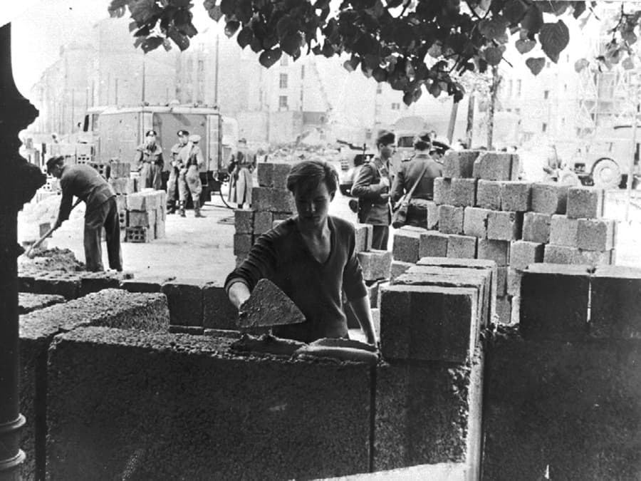 Na fotografii z 13. augusta 1961 robotník stavia časť múru medzi východnou a západnou časťou Berlína.