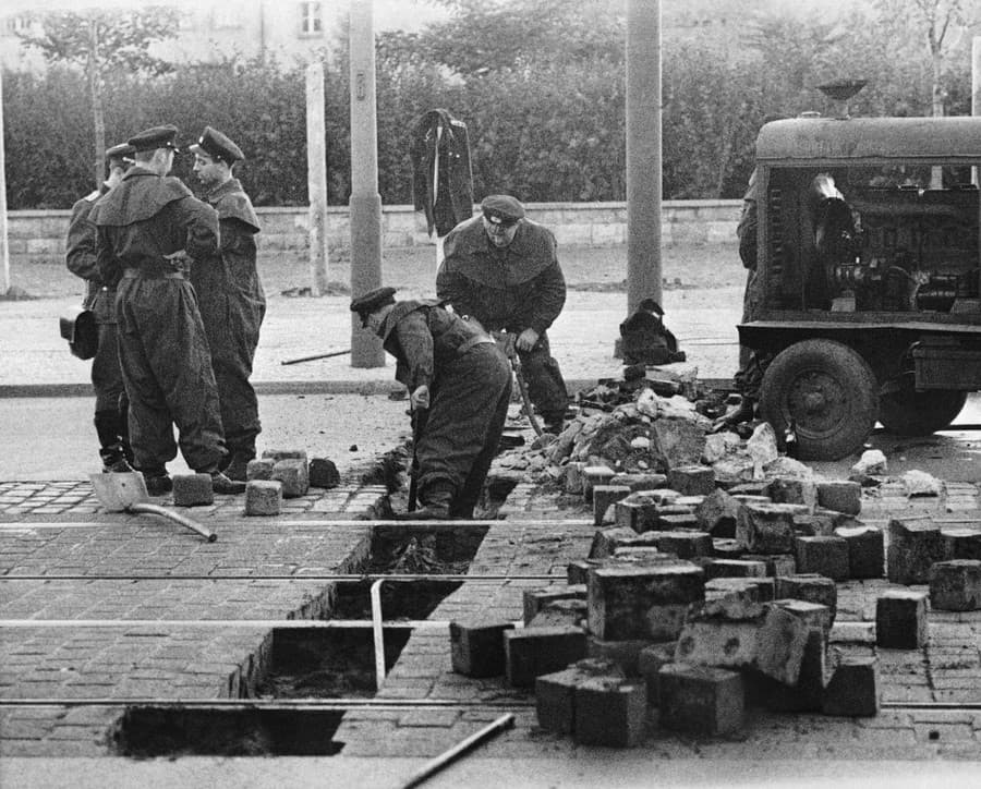 Na fotografii z 13. augusta 1961 východonemeckí vojaci premiestňujú dlaždice na ulici Friedrich Strasse vo východnom Berlíne.