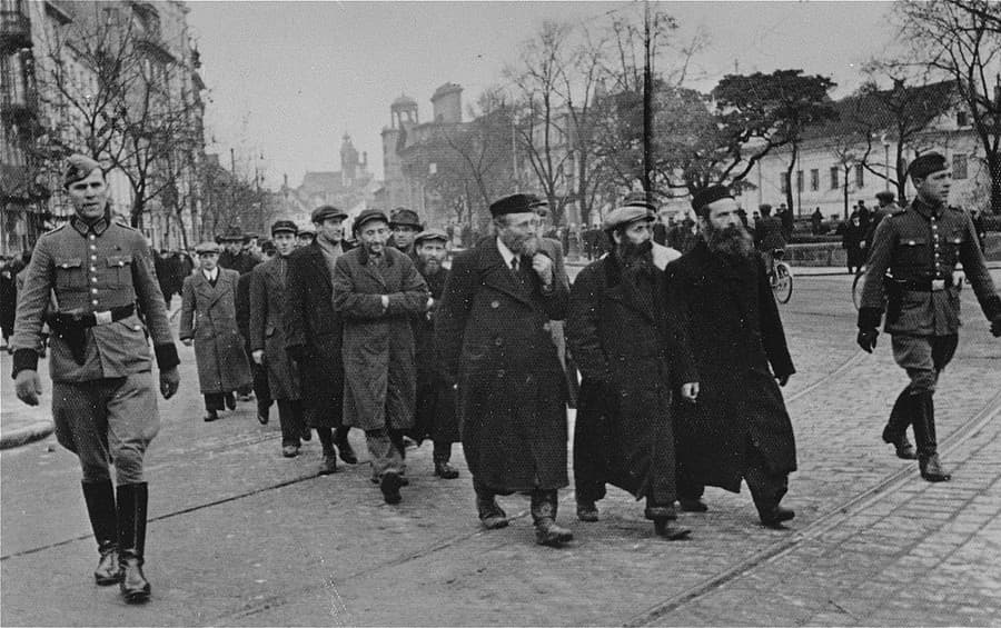 Židovskí muži sú eskortovaní na nútené práce po ulici Krakowskie Przedmiescie, marec 1940