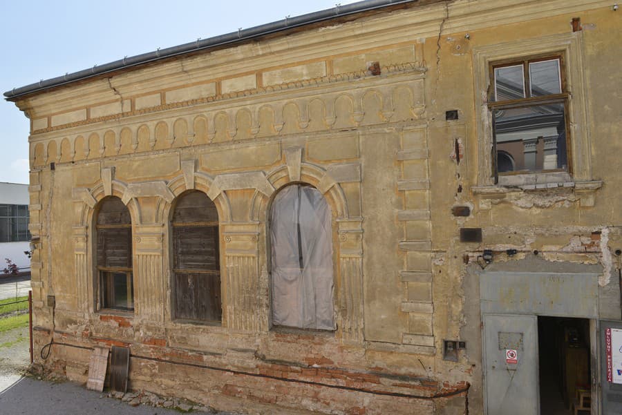 Jedna zo schátralých budov židovského suburbia, v pravom okne sa odráža zrekonštruovaná synagóga