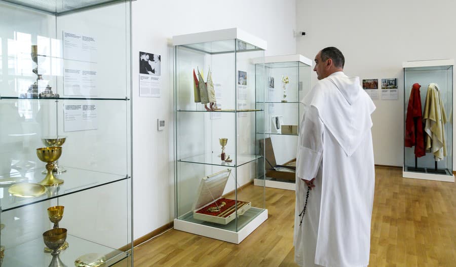 Duchovný predstaviteľ si prezerá vitríny počas slávnostného otvorenia výstavy s názvom Dary pápežov Slovensku