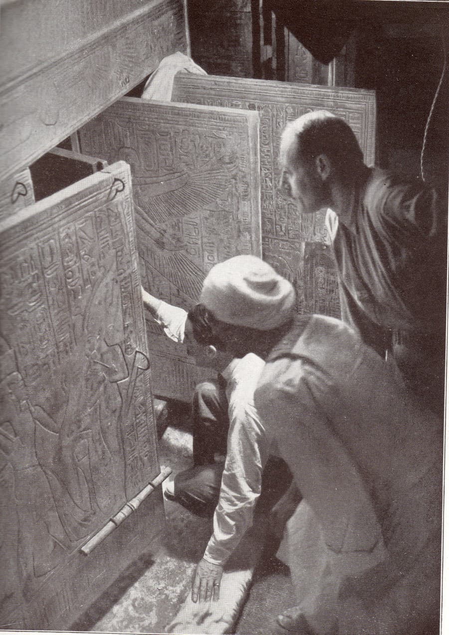 Kľačiaci Howard Carter, egyptský robotník a Arthur Callender pri dverách Tutanchamonovej hrobky, 1924