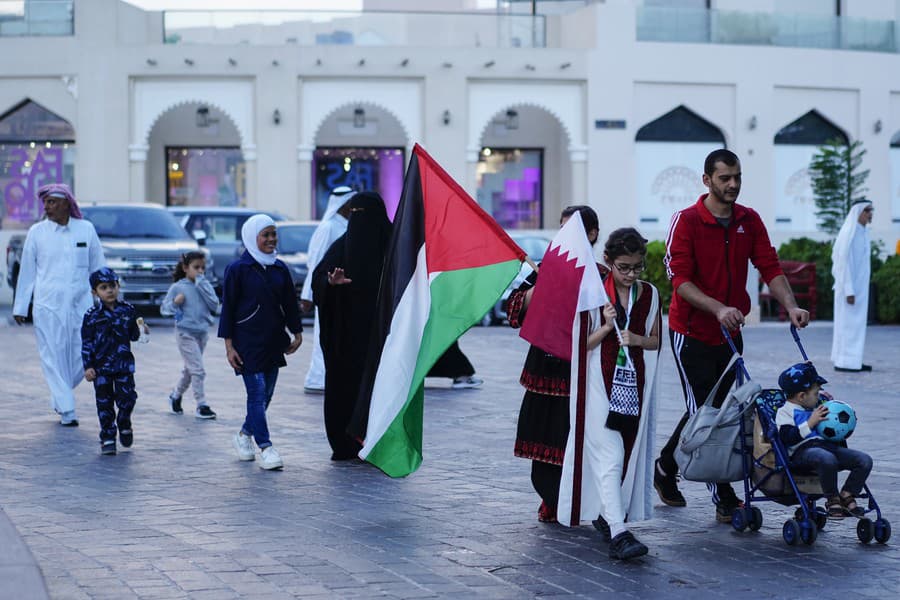 Ľudia kráčajú s palestínskou (uprostred) a katarskou zástavou v kultúrnej dedine Katara.