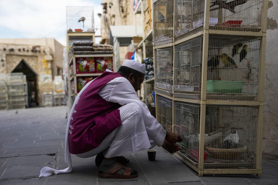Muž kŕmi vtáky v klietkach na trhu Waqif.