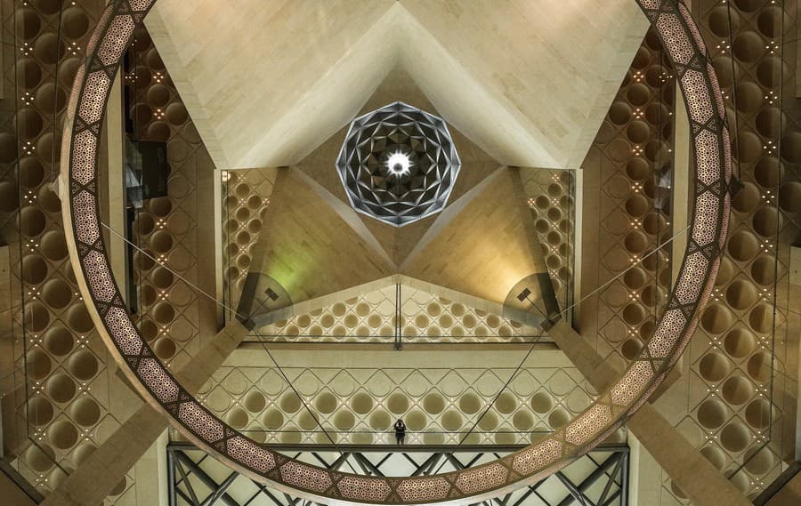 Muž stojí na hornom poschodí vo vstupnej hale Múzea islamského umenia v Dauhe