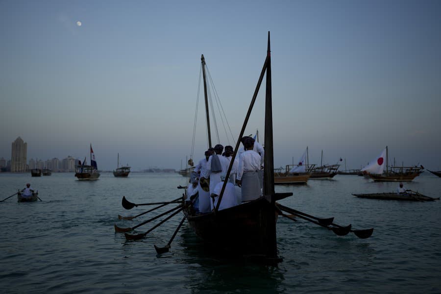 Muži stoja na lodi na pláži Katara.