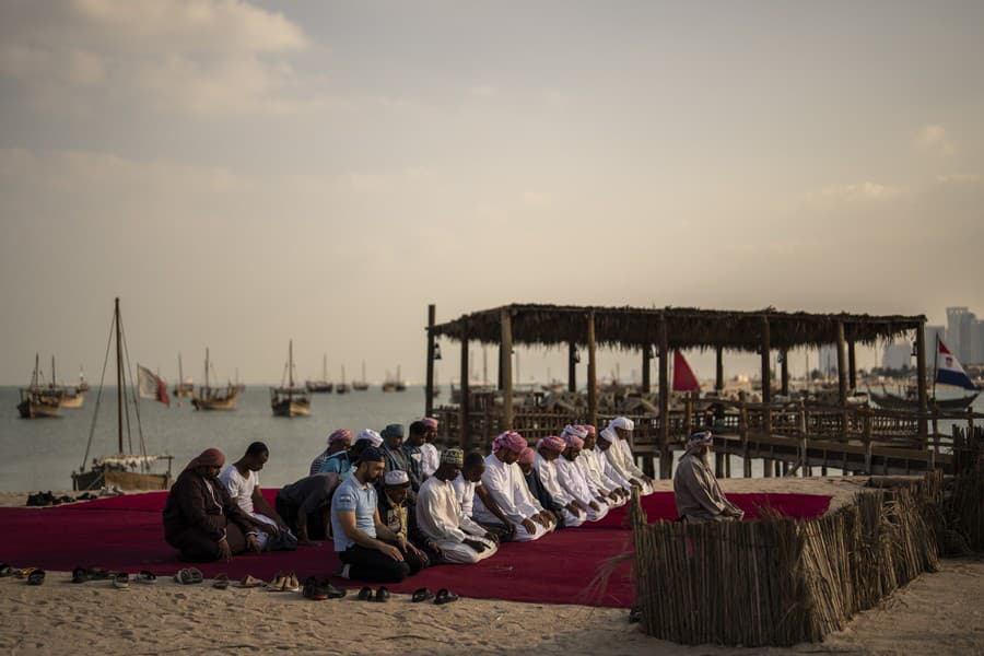 Muži sa modlia na pláži Katara.