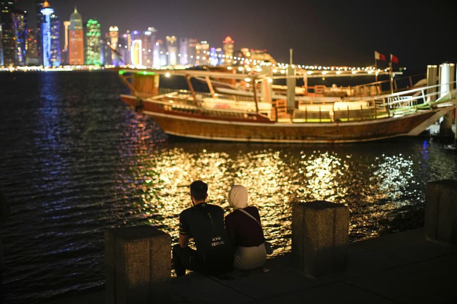 Pár sedí pri mori na promenáde Corniche.