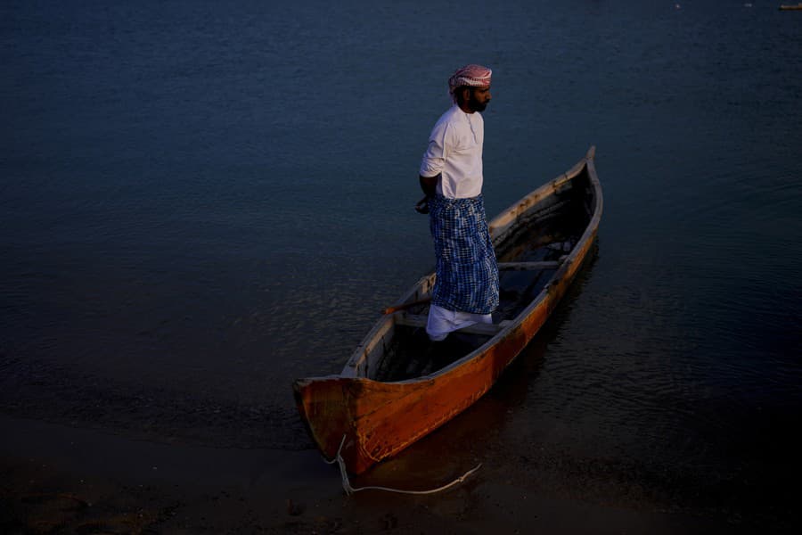 Muž stojí na lodi na pláži Katara.