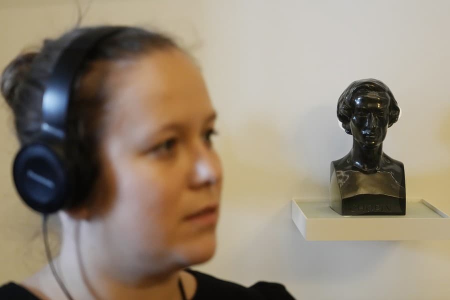 Žena stojí pri malej buste  Fryderyka Chopina v zrekonštruovanom múzeu
