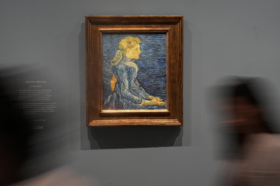 Ľudia prechádzajú okolo olejomaľby od Vincenta Van Gogha s názvom Adeline Ravouxová namaľovanej 22. júna 1890
