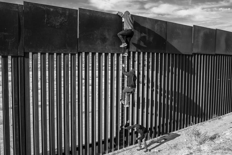 Migranti používajú podomácky vyrobený rebrík, aby s pomocou pašeráka preliezli časť hraničného múru. Ciudad Juárez, Mexiko, 1. apríla 2021.