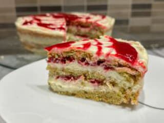 Svieža a krehká pistáciová torta s malinovou omáčkou s kúskami pistácii je dokonalým dezertom!