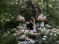 Na prvej fotografii je pár videný v rozprávkovej záhrade obklopený ružovými a bielymi ružami, zatiaľ čo Travis kľačí na jednom kolene. 