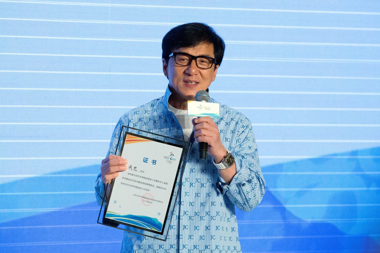 Jackie Chan pri preberaní certifikátu za spoluúčasť na tvorbe piesne pre kandidatúru Pekingu na usporiadanie ZOH 2022