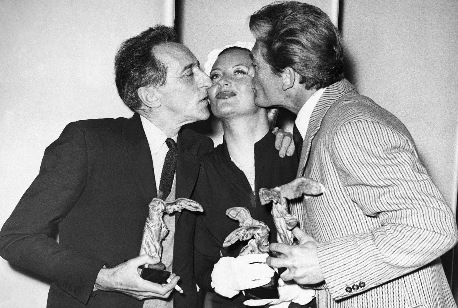 Jean Cocteau (vľavo) a francúzsky herec Jean Marais bozkávajú francúzsku herečku Michele Morganovú po prevzatí ceny na filmovom festivale v Cannes