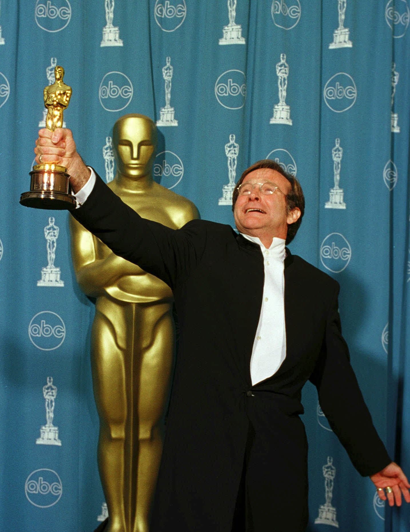 Robin Williams sa teši z Oscara, ktorého získal za vedľajšiu rolu v snímke Dobrý Will Hunting (Zdroj: TASR/AP Photo/Long Photography, HO)