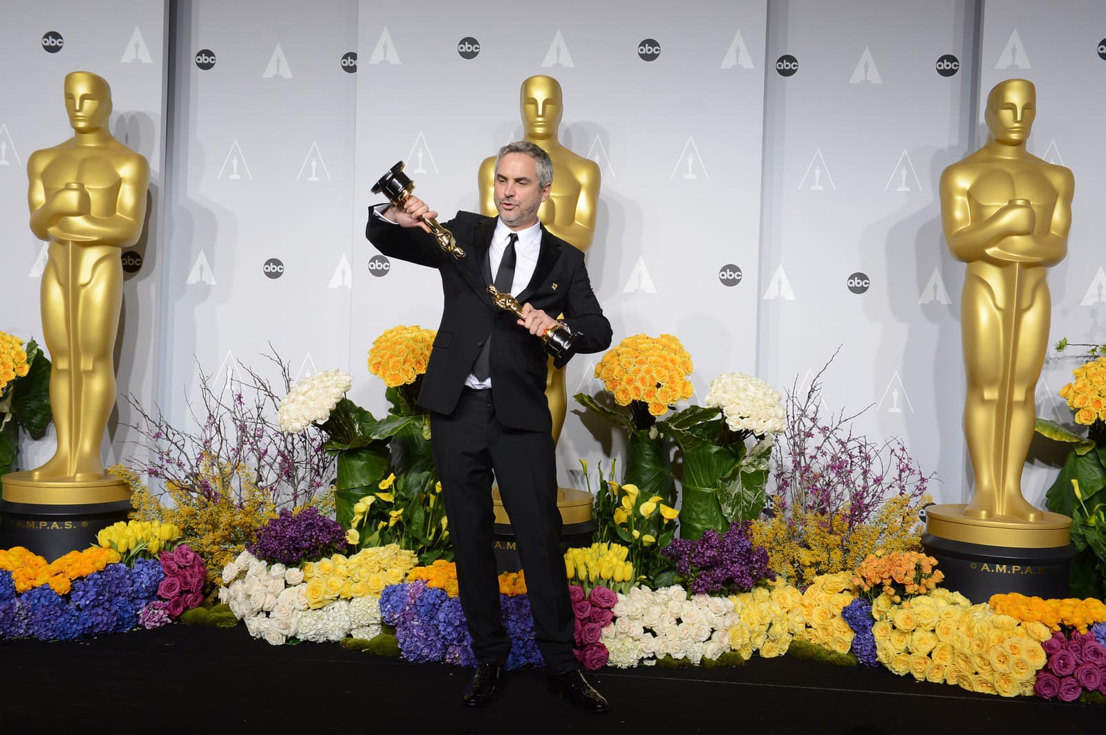 Alfonso Cuarón pózuje so soškami Oscarov v kategórii najlepšia réžia a najlepší strih za snímku Gravitácia (Zdroj: Photo by Jordan Strauss/Invision/AP)