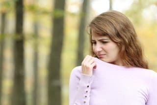 Disgusted woman smelling clothes