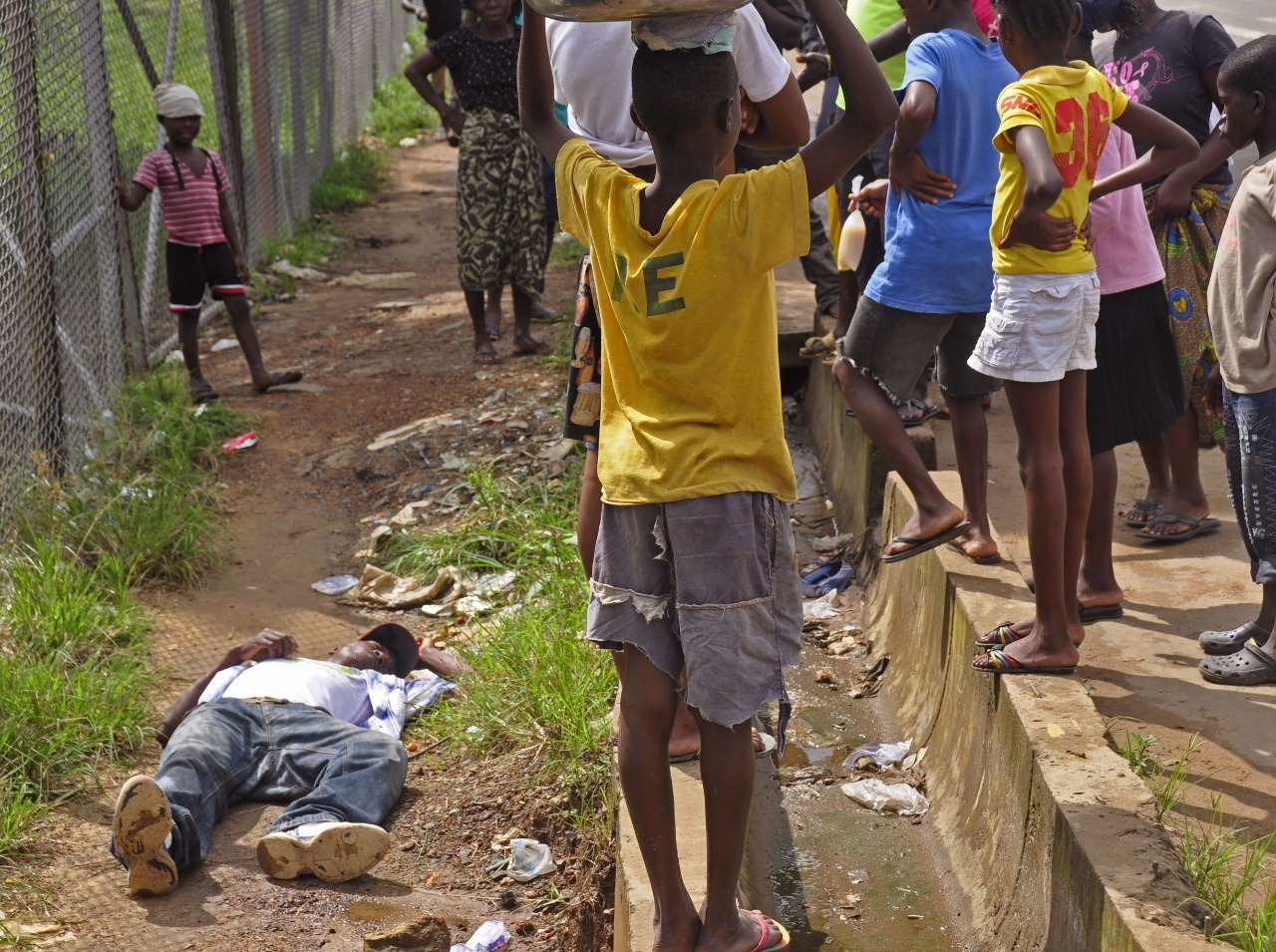 Deti obklopujú človeka, ktorý padol pri chôdzi na zem, podozrivý z nakazenia vírusom Ebola v meste Monrovia.